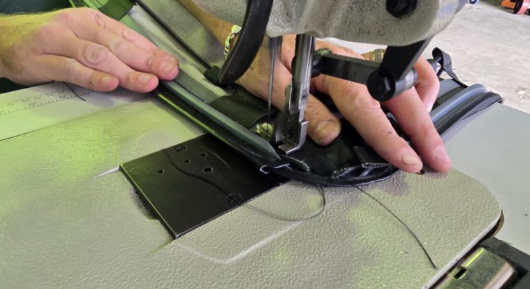 A seam on a dark cover being re-stitched on an industrial sewing machine